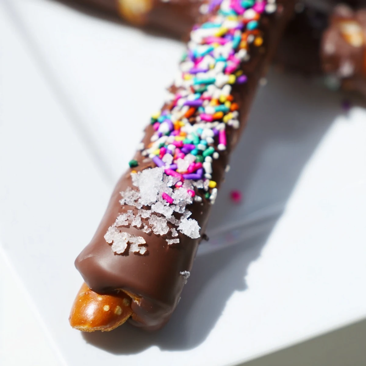 Close-up of Chocolate Dipped Pretzels with Sea Salt and Sprinkles highlighting flaky crystals and shimmering sprinkles on melted coating.