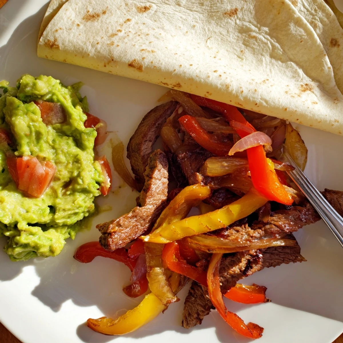 Sizzling Beef Fajitas with Guacamole feature marinated beef strips, colorful peppers, and onions piled on warm tortillas with creamy avocado.