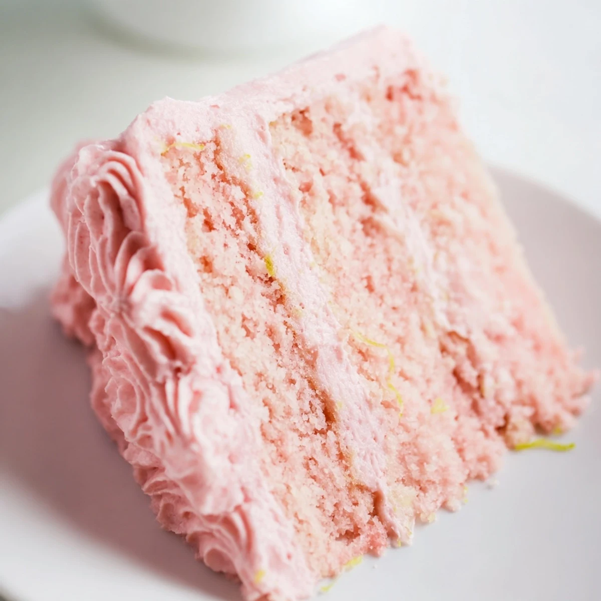 Slices of the Pink Lemonade Layer Cake reveal moist crumb and tangy buttercream, perfect for summer celebrations.