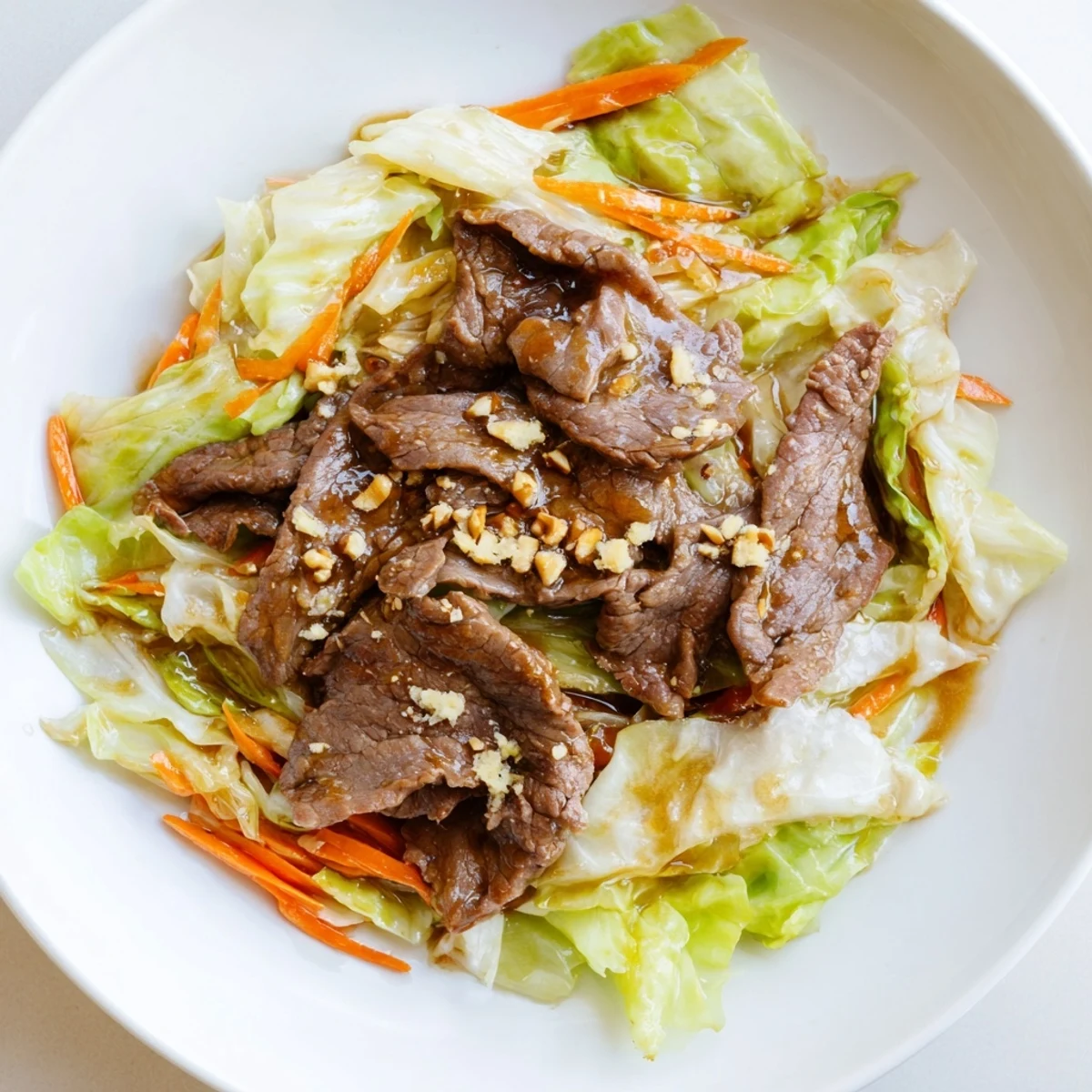 Heaping plate of tender beef, shredded cabbage, and carrots in a fragrant stir fry, ready to serve.  