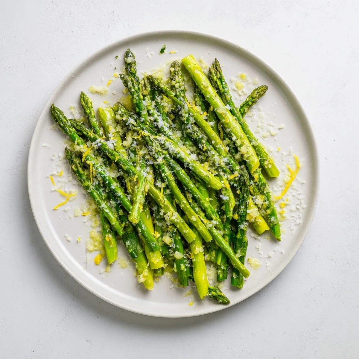 Vibrant green asparagus spears glisten with lemon juice and minced garlic in a skillet, ready to be tossed with Parmesan cheese for a zesty side dish.