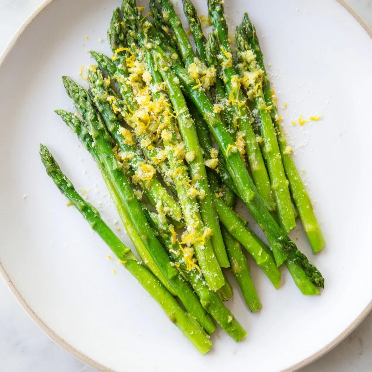 Tender asparagus sautéed with garlic and lemon, then sprinkled with grated Parmesan, served warm as a simple Mediterranean-inspired vegetarian side dish.