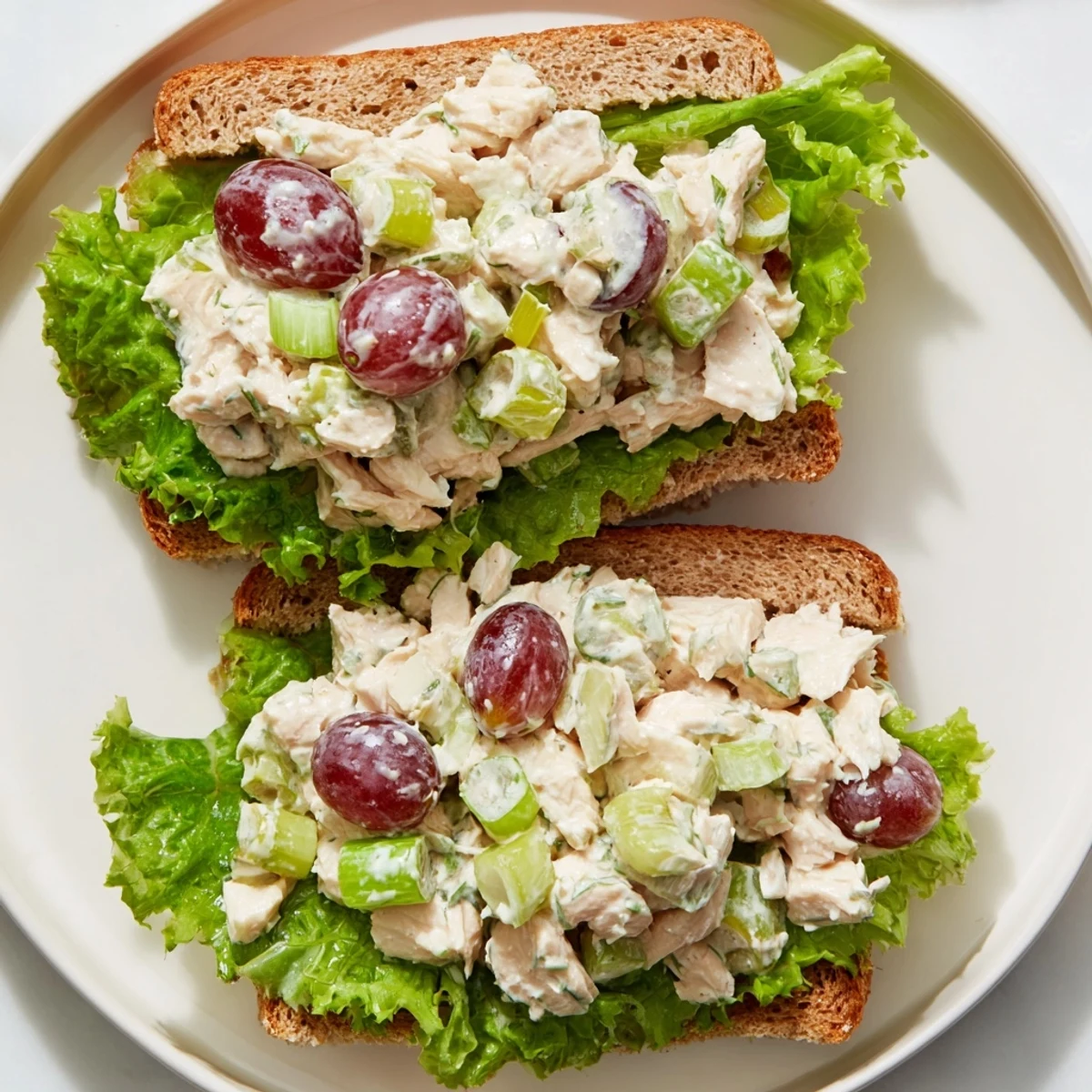 Freshly made Chicken Salad Sandwich with Grapes stacked high with crisp lettuce on toasted whole wheat bread.
