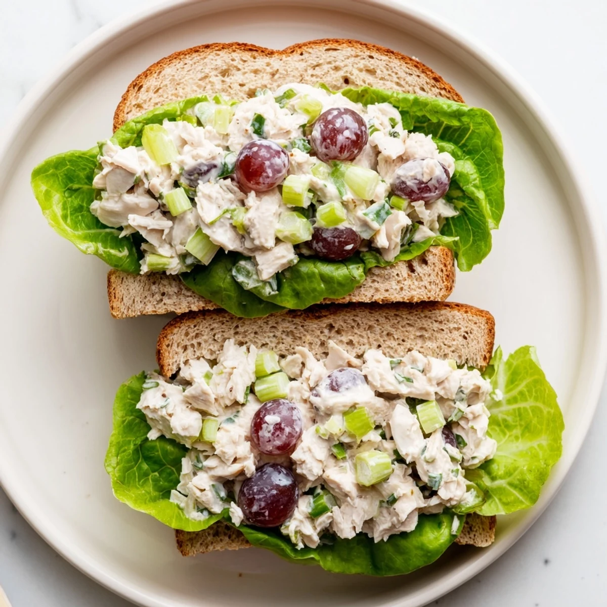 Creamy Chicken Salad Sandwich with Grapes featuring juicy halved red grapes and crunchy celery.