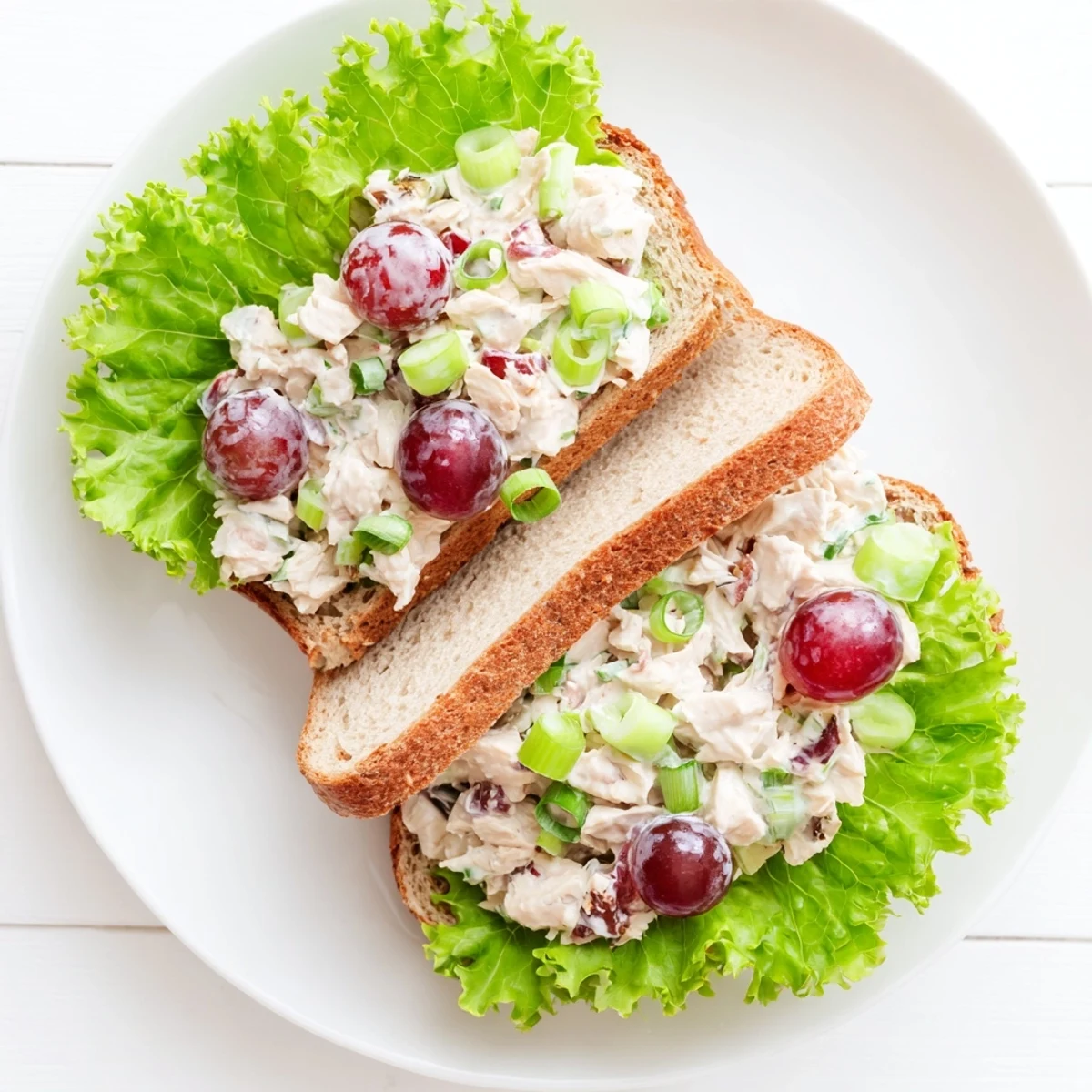 Ready-to-serve Chicken Salad Sandwich with Grapes cut in half showing a hearty chicken filling.