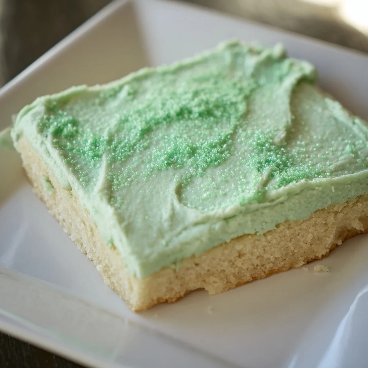 Ready-to-serve Shamrock Cookie Bars on a platter, showcasing creamy green frosting and a tender, golden-brown texture.  
