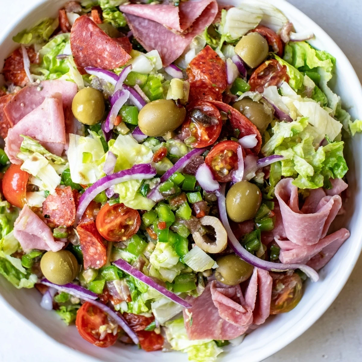 Genoa salami, mortadella, provolone, and mozzarella strips tossed with tangy Italian dressing create a hearty New Orleans Muffuletta Salad.