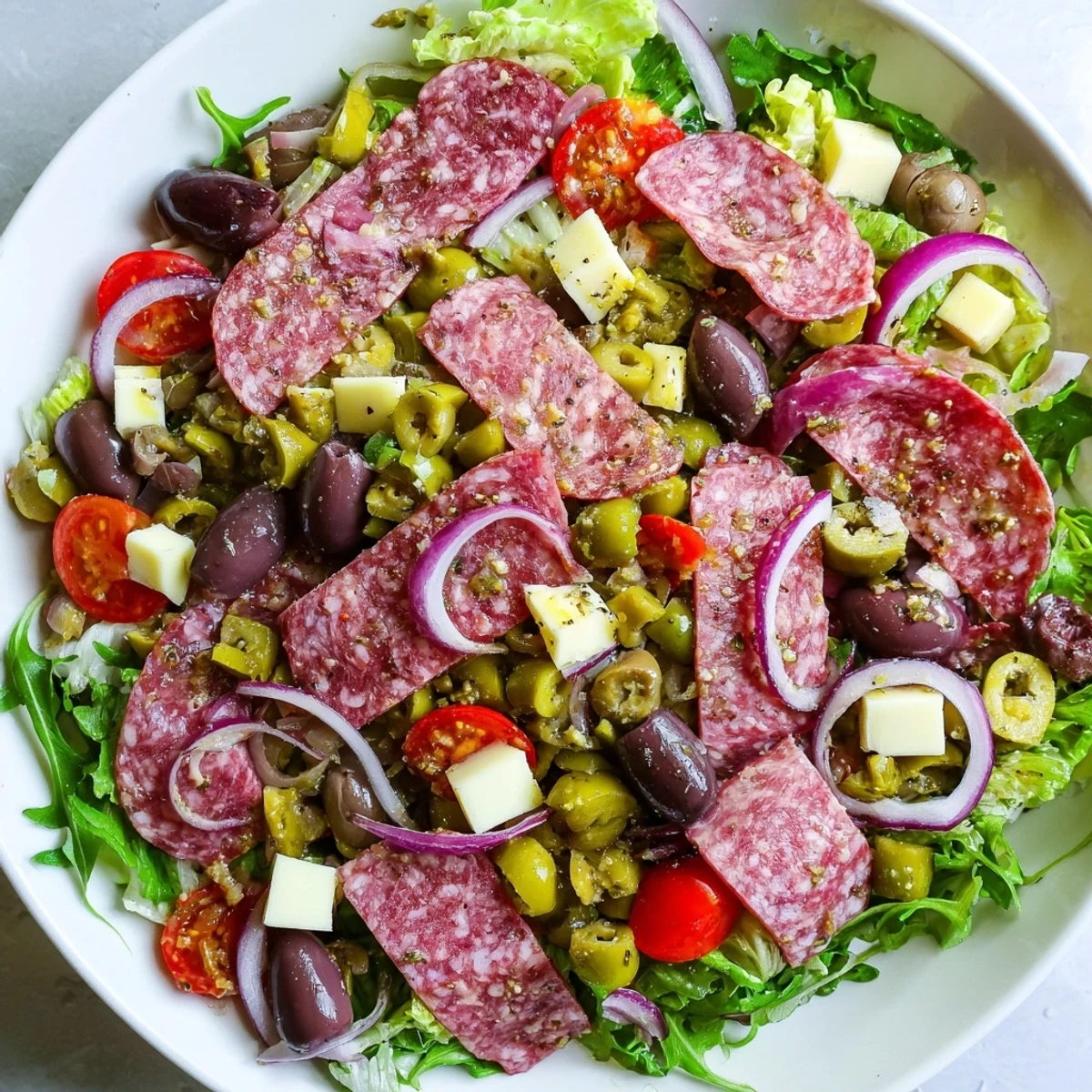 Enjoy this deconstructed New Orleans Muffuletta Salad served in a bowl with crunchy toasted bread on the side.