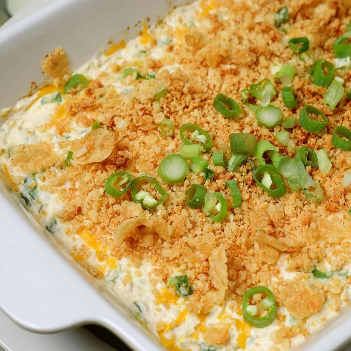A close-up of creamy Jalapeno Popper Dip in a ceramic dish, garnished with fresh jalapeno slices and green onions for a spicy, cheesy appetizer.  
