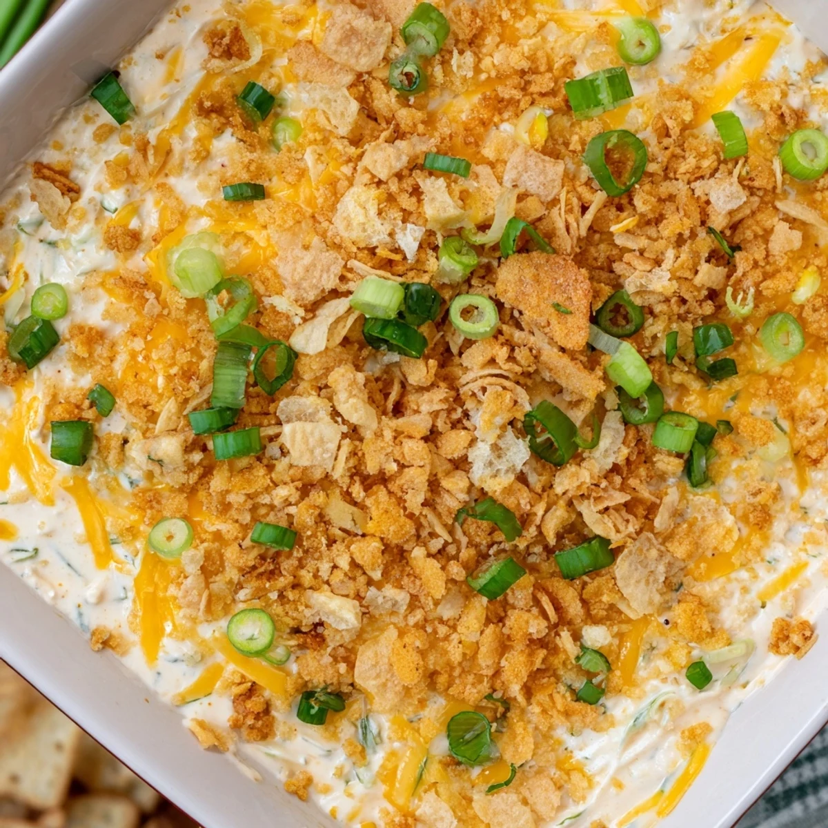 Jalapeno Popper Dip served in a baking dish alongside a platter of crunchy crackers and sliced baguette, perfect for game day gatherings.
