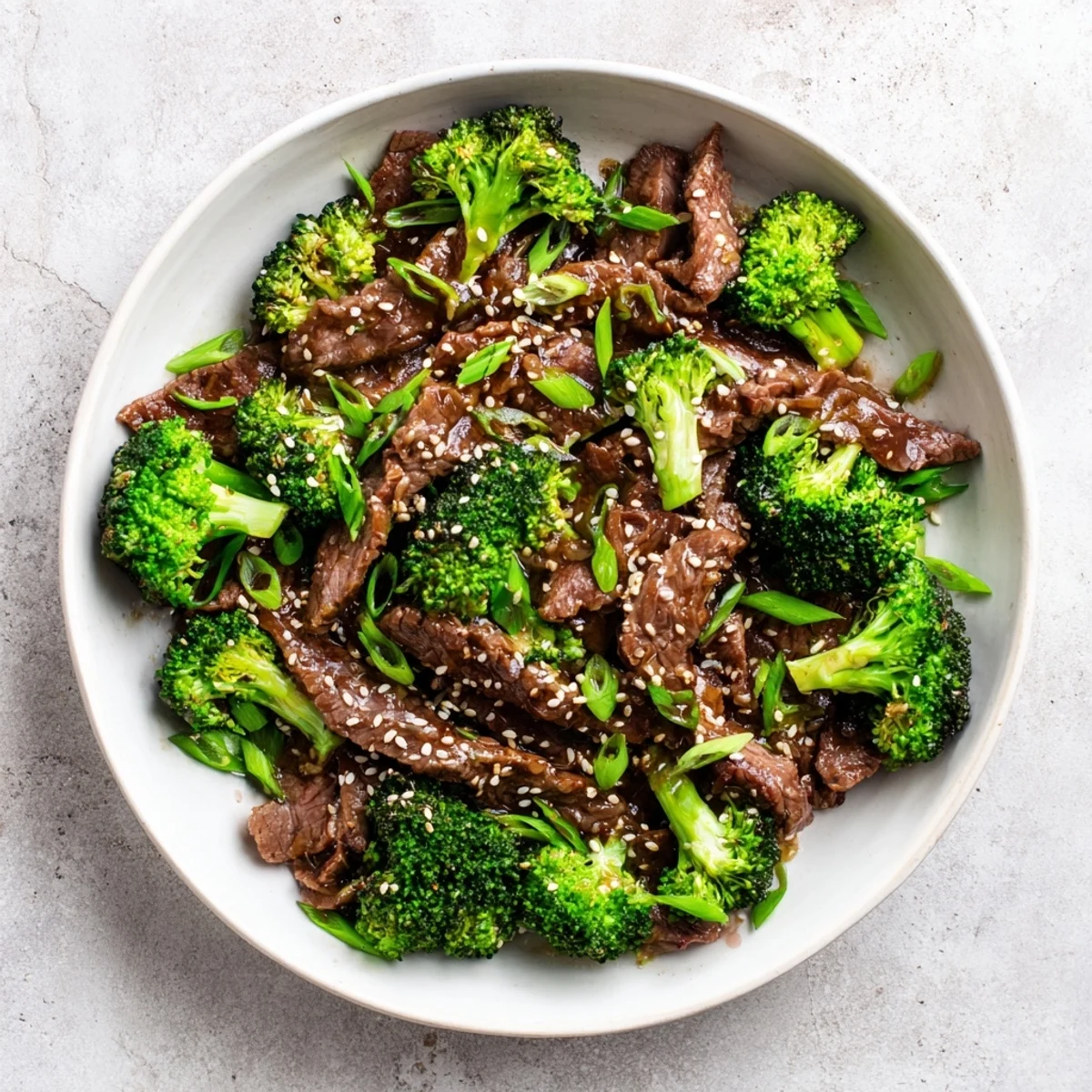 A close-up view of tender beef and broccoli mingling with a rich, dark ginger sauce, garnished with sesame seeds.