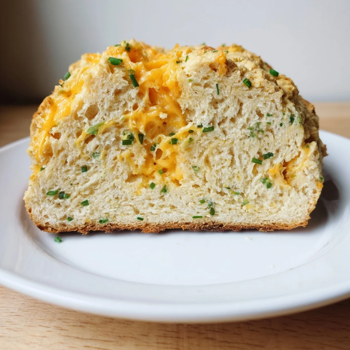 Savory Cheddar & Chive Irish Soda Bread on a rustic wooden board, its tender crumb and melted cheese bits inviting for a comforting soup side.