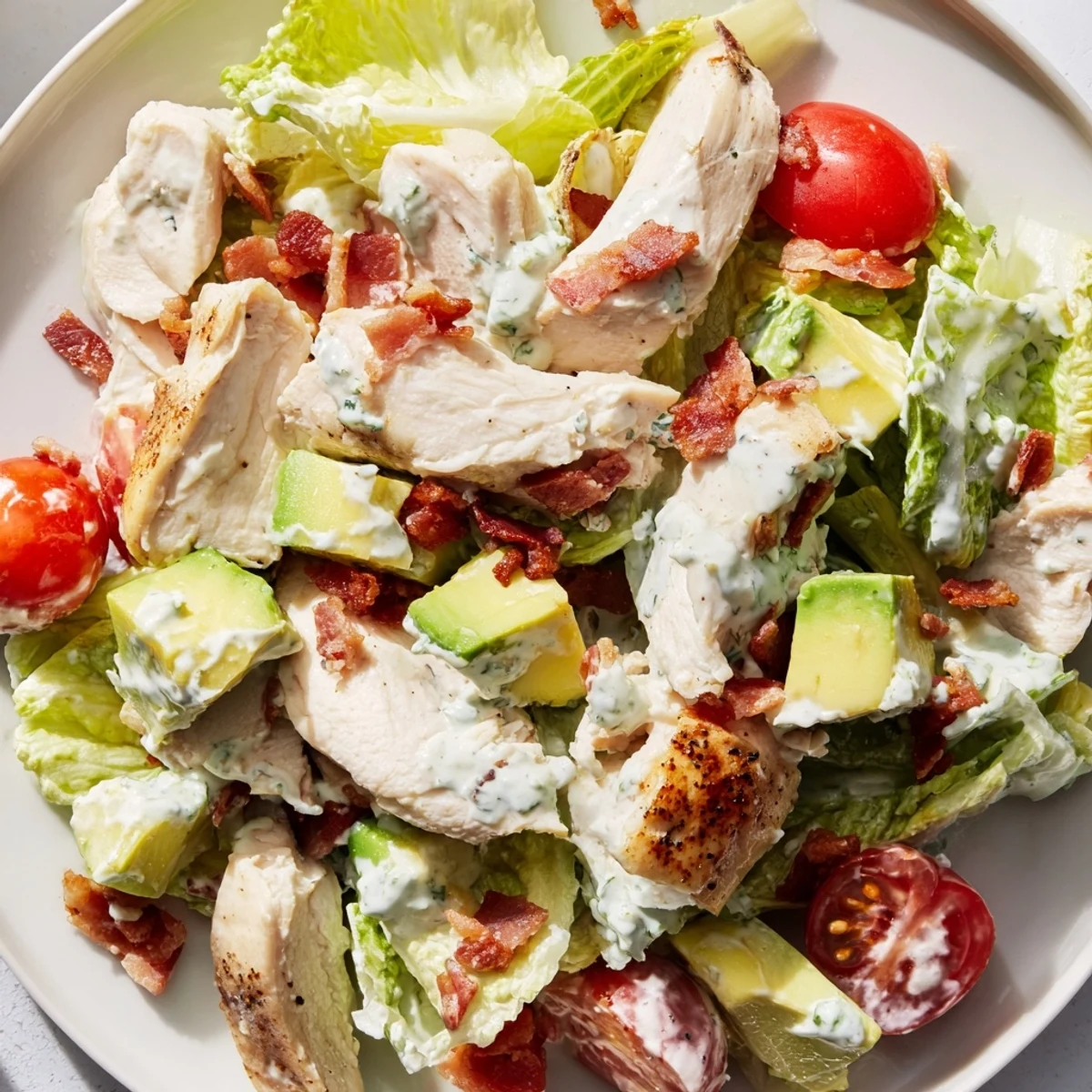Juicy cherry tomatoes and creamy avocado slices garnish the hearty BLT Chicken Salad bowl.