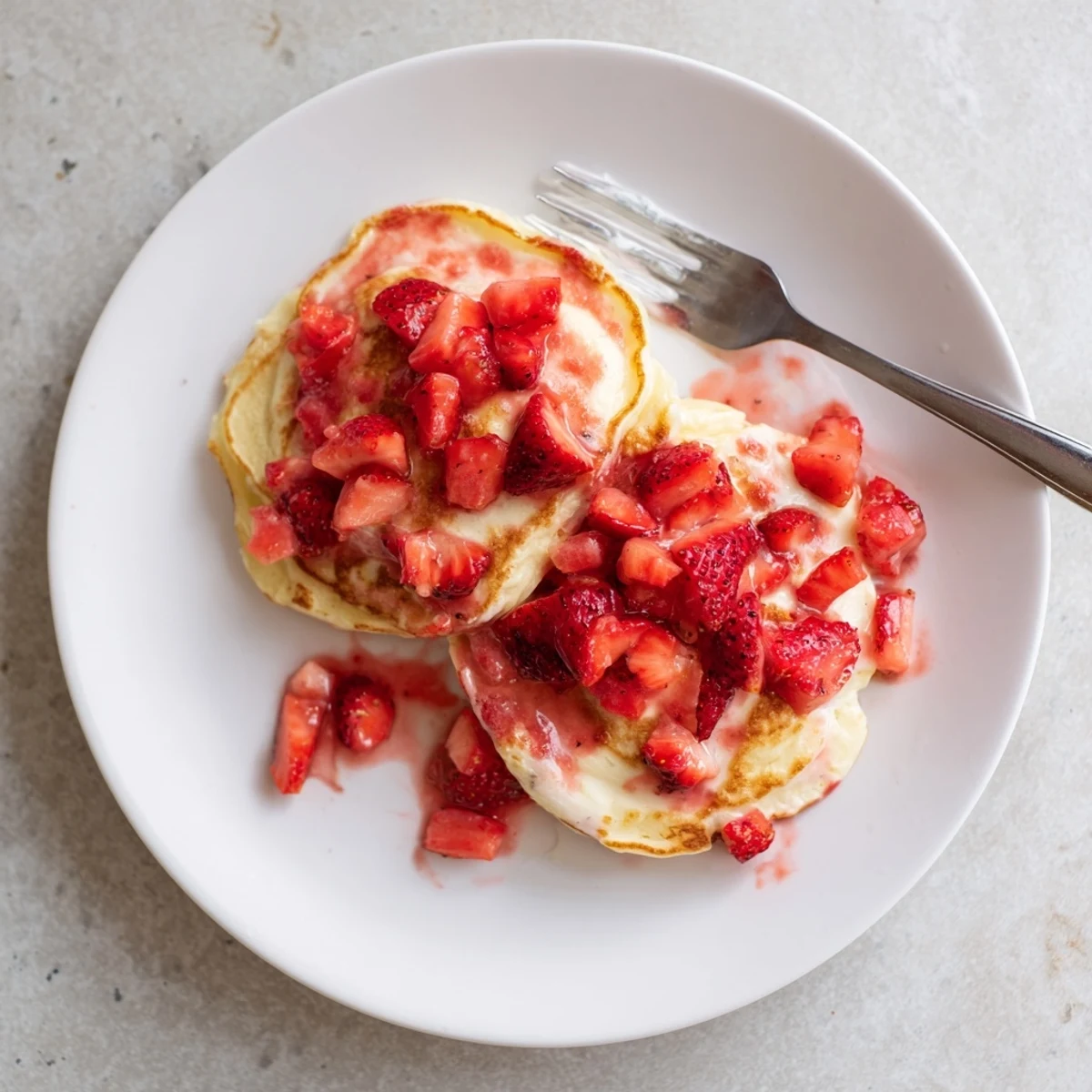 Fluffy Strawberry Cheesecake Pancakes stack high with a creamy swirl and fresh berry sauce ready to serve for breakfast.