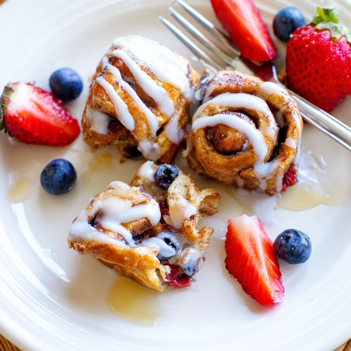 Golden-brown Cinnamon Roll French Toast Bites in a skillet with maple syrup and powdered sugar.
