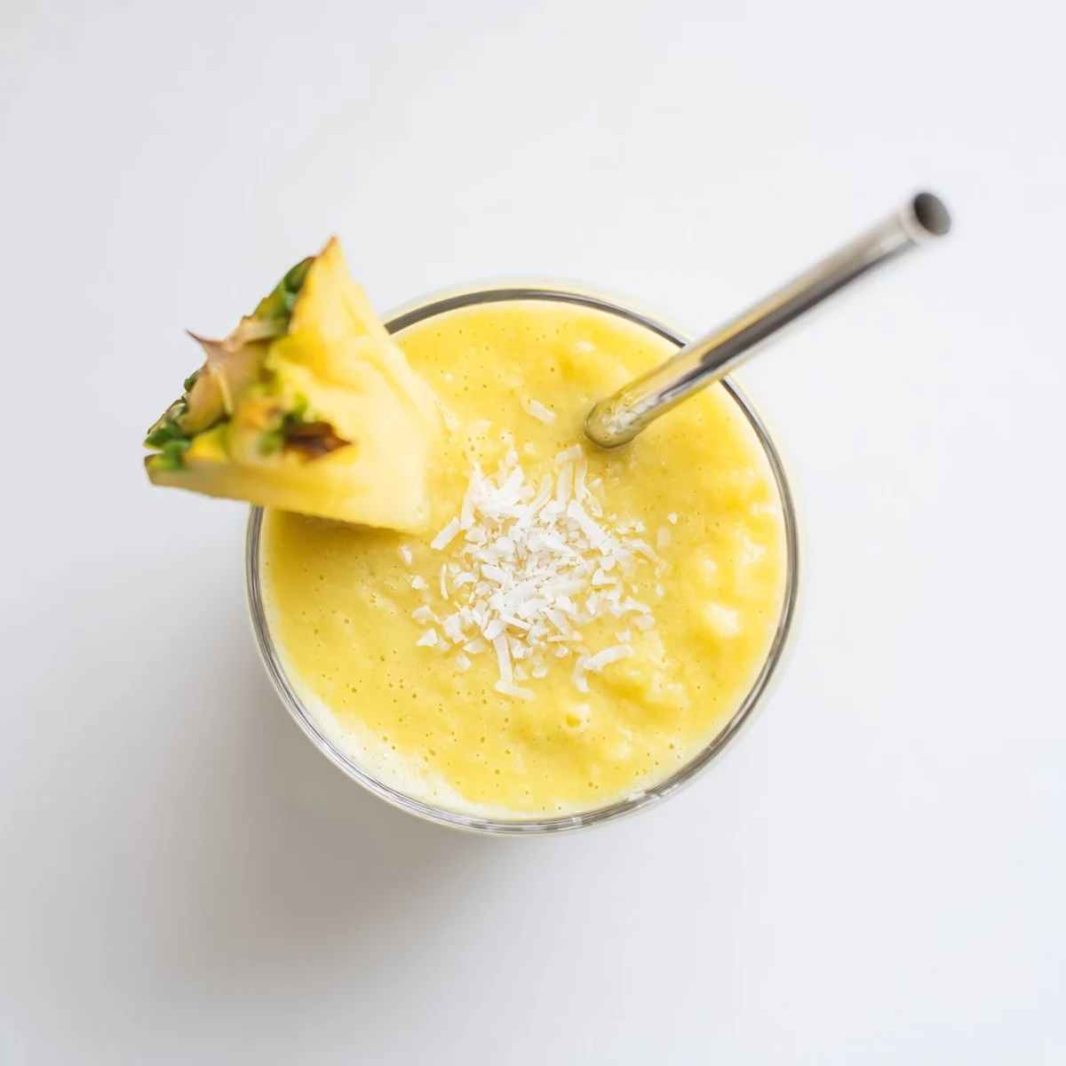 Two glasses of chilled Pineapple Coconut Smoothie with shredded coconut topping, ideal for a healthy tropical snack.