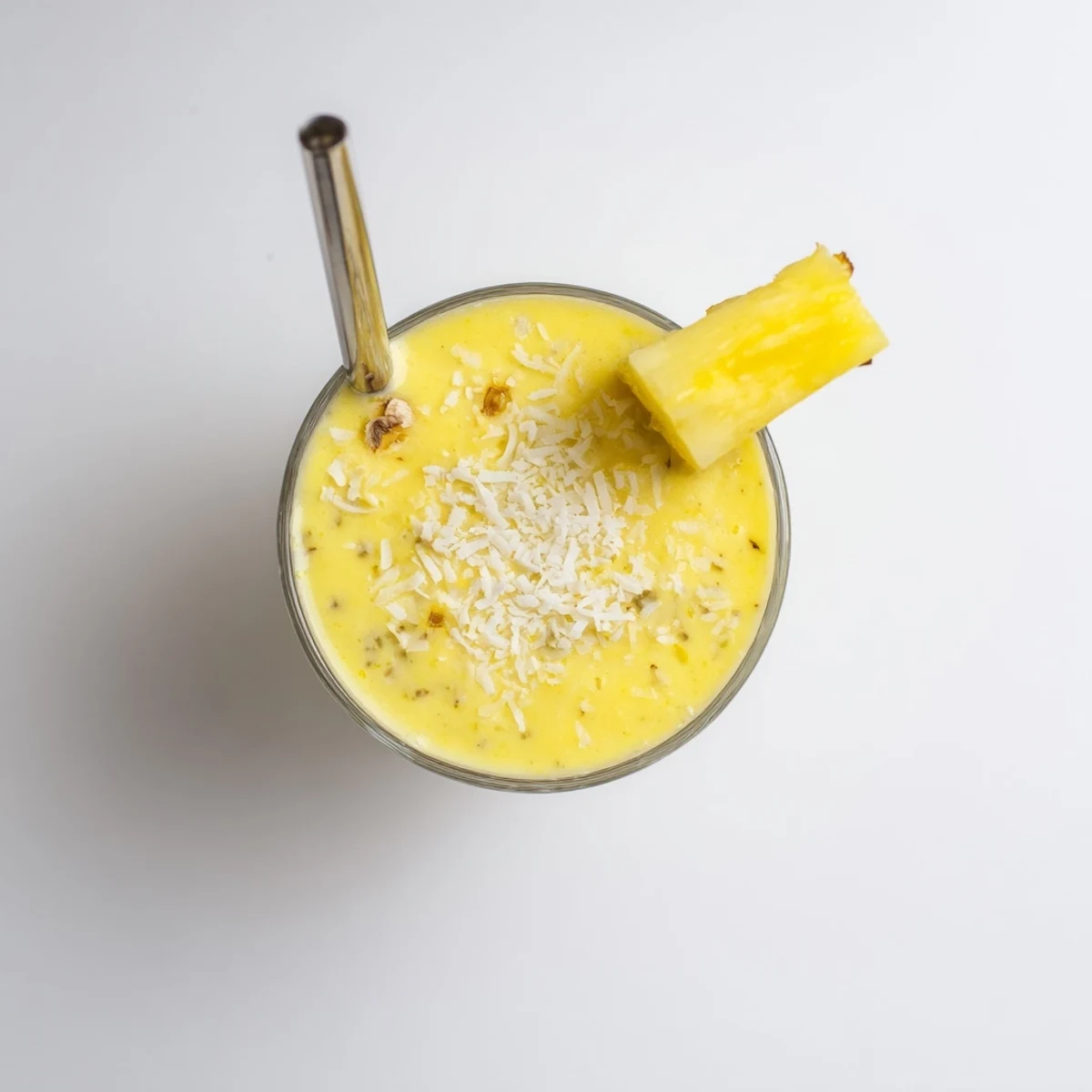 Fresh Pineapple Coconut Smoothie in a blender pitcher showing creamy texture, served over ice for extra refreshment.