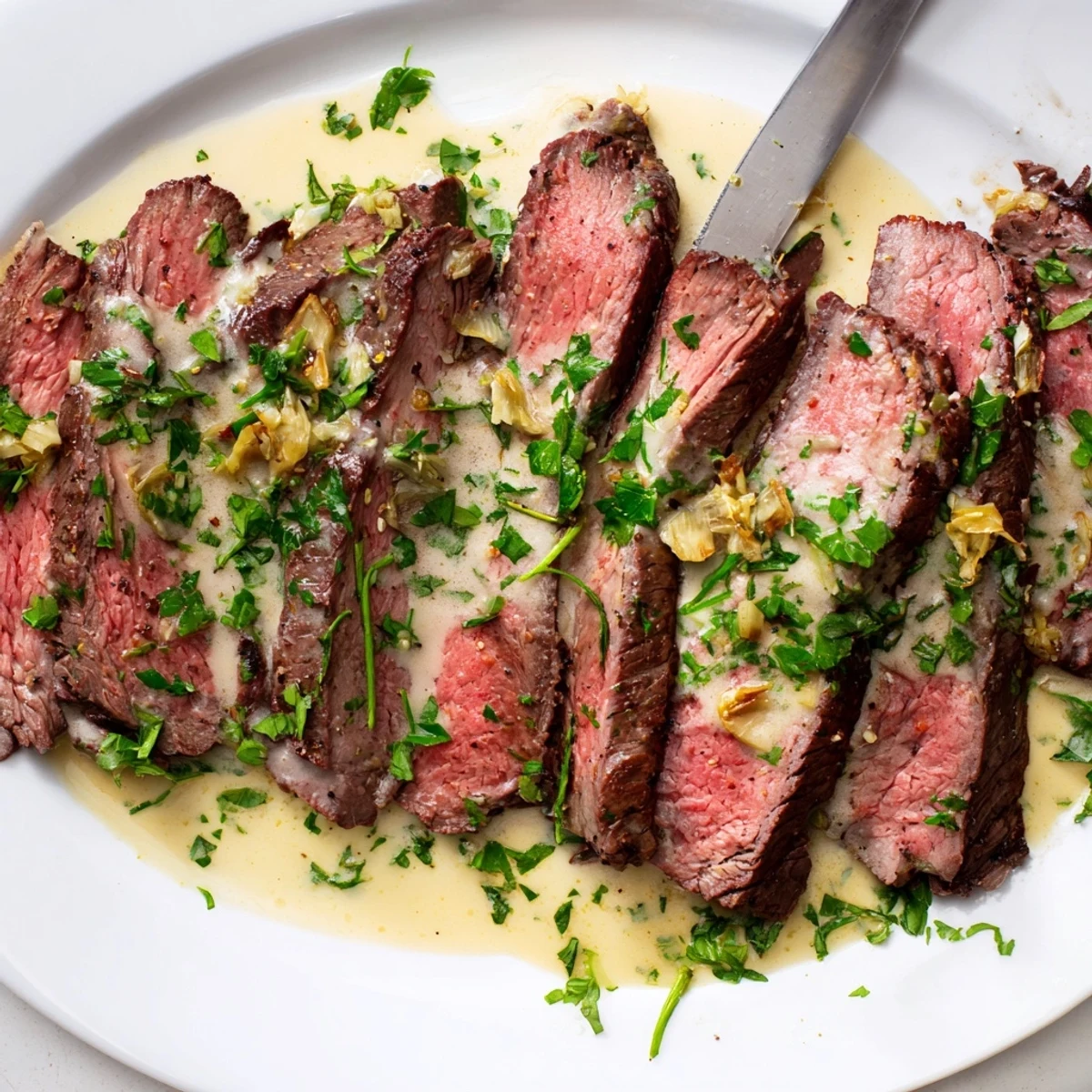 Tender slices of flank steak with velvety roasted garlic sauce, served beside golden roasted potatoes.