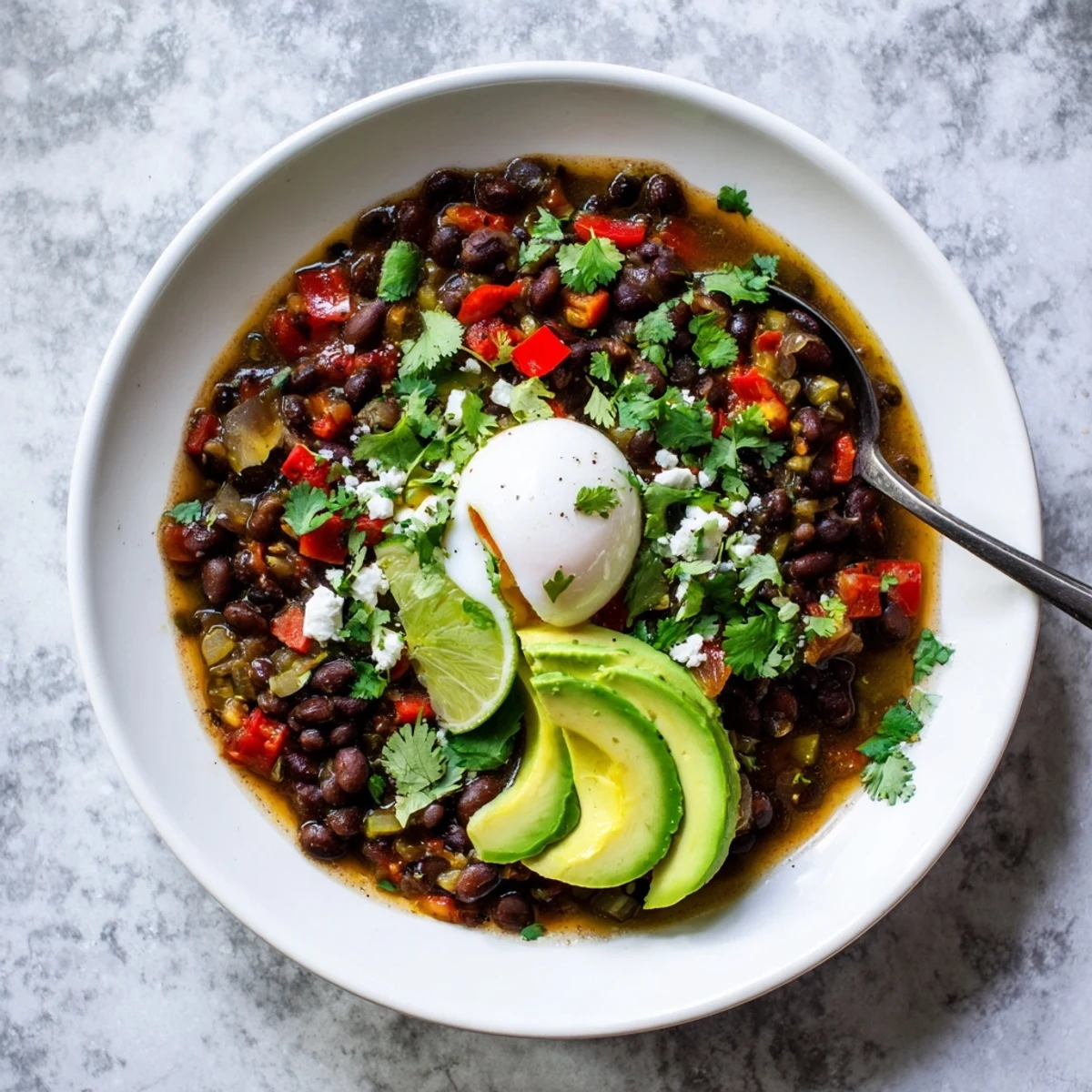 Steaming Mexican Braised Beans With Soft Boiled Egg topped with crumbled queso fresco and lime wedges.