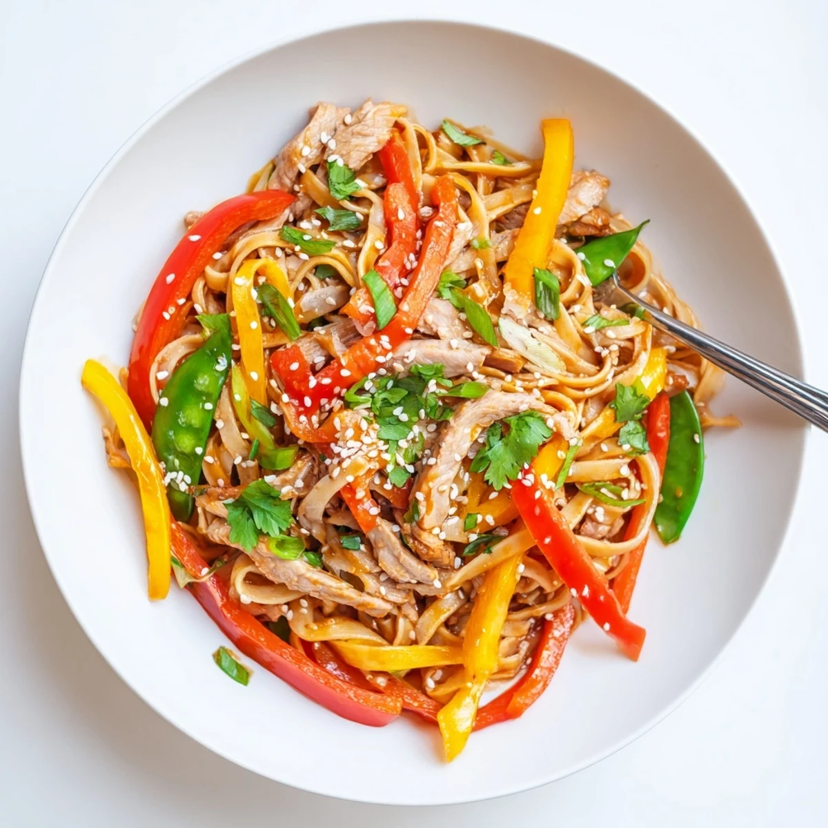 A close-up of Sweet Chilli Turkey Noodle Stir Fry with vibrant red bell peppers, crisp snap peas, and tender turkey slices in a glossy, sweet chili sauce.