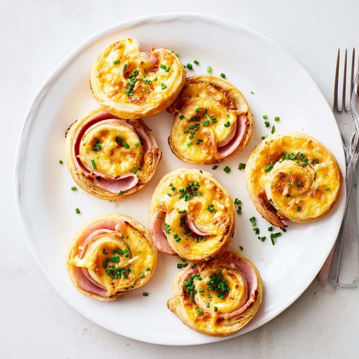 Savory Easter Ham Cheddar Pinwheels brushed with egg wash and garnished with fresh herbs