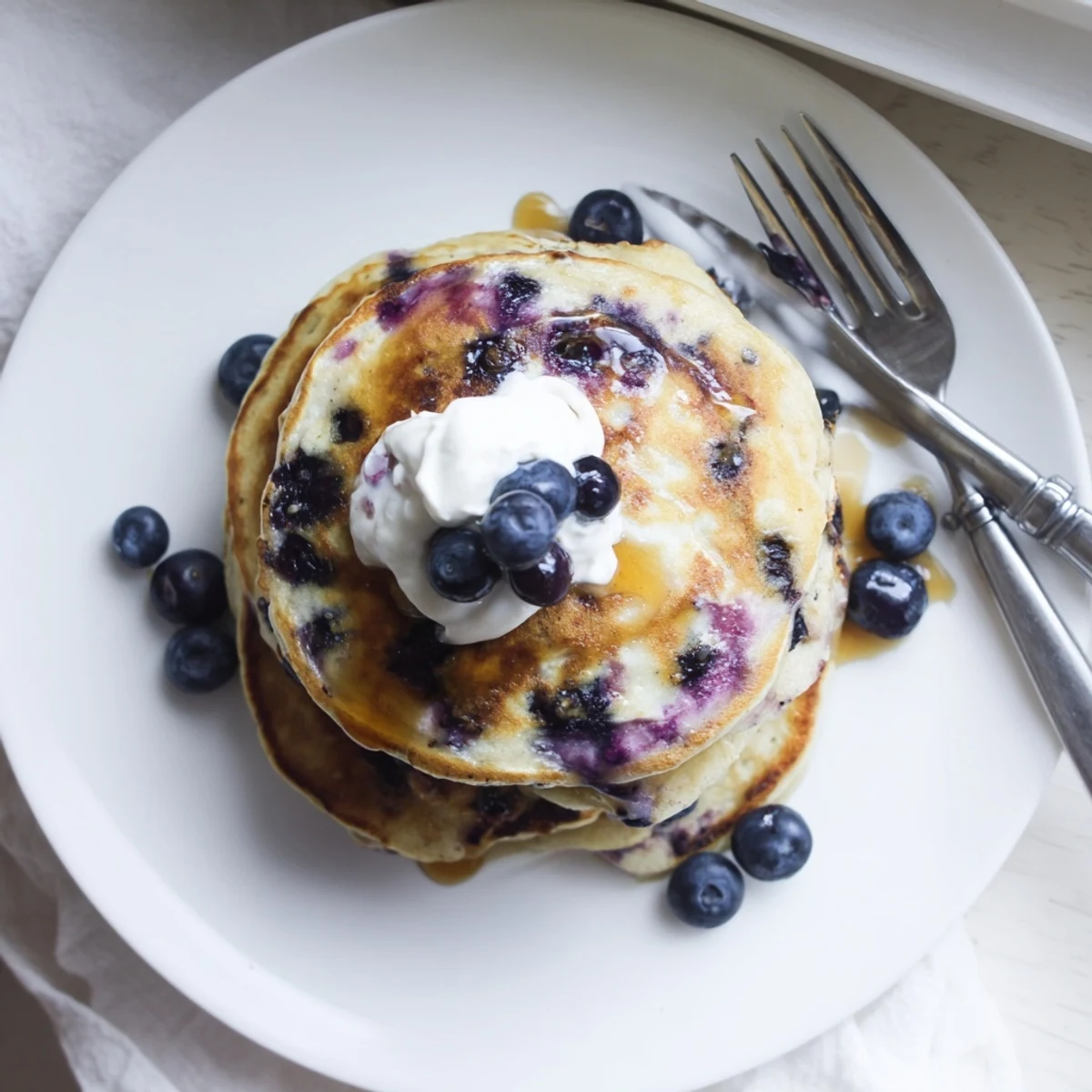 Steaming Greek yogurt blueberry pancakes topped with extra yogurt and sweet blueberry garnish