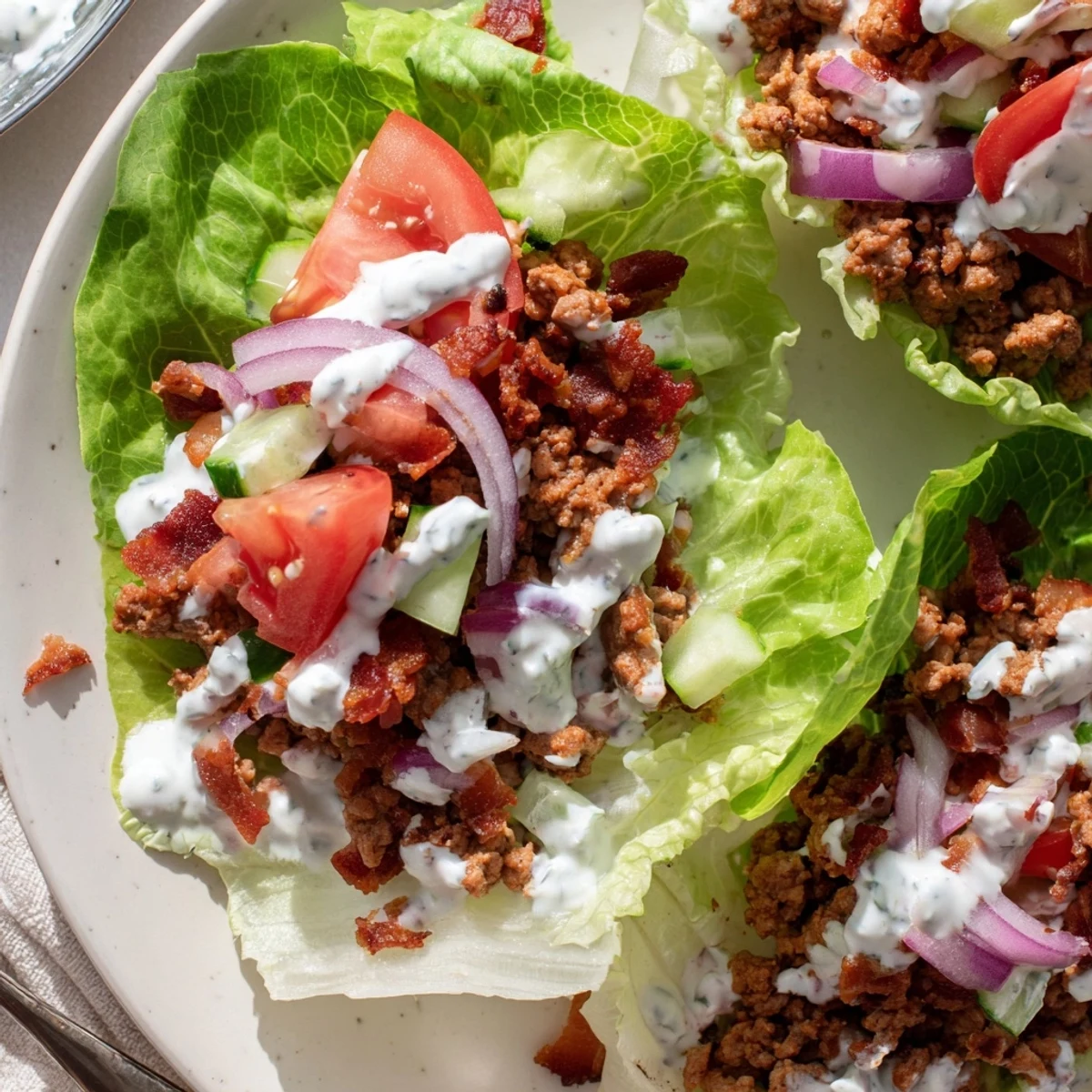 Low-carb lettuce wraps loaded with juicy seasoned proteins and fresh vegetables under a generous ranch dressing drizzle