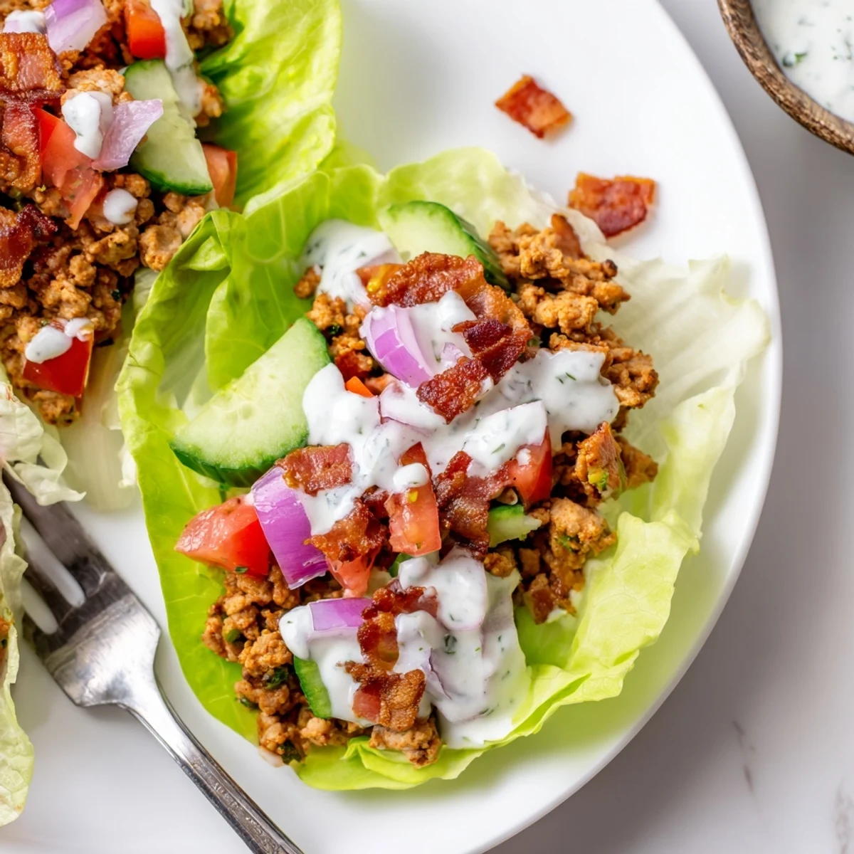 Hearty chicken, beef and bacon lettuce wraps featuring crisp vegetables and smooth ranch on a serving platter