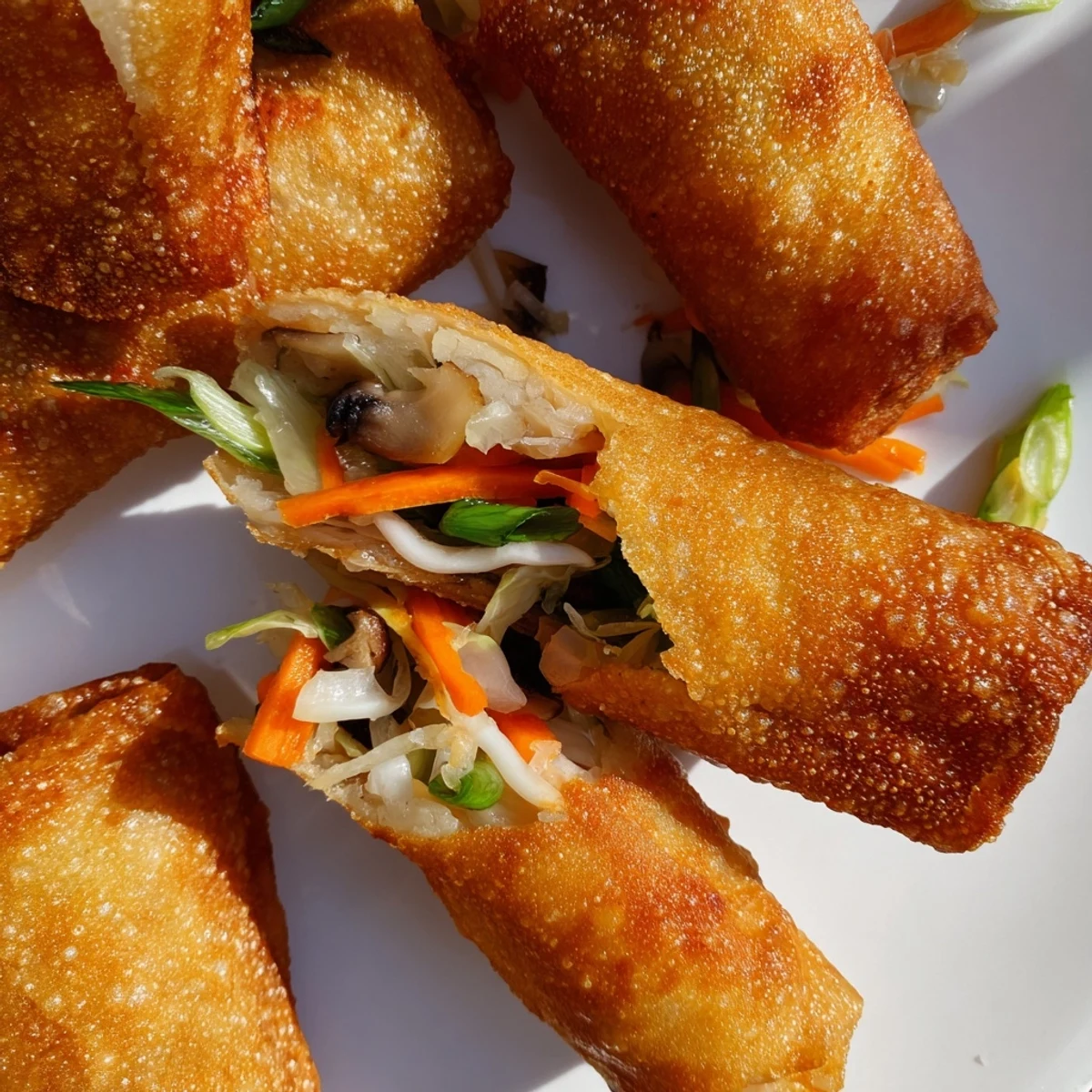 Golden crispy spring rolls with vegetable filling served on white plate