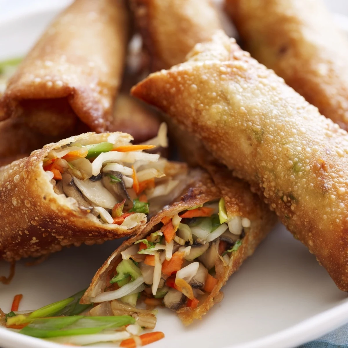 Plate of golden crispy spring rolls filled with savory vegetables and aromatics