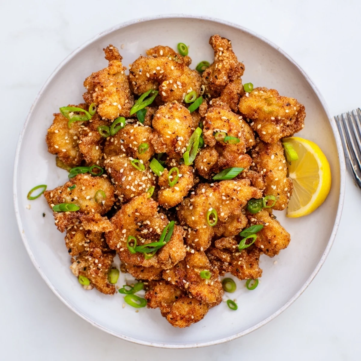 Golden brown crispy Hawaiian Mochiko Chicken pieces garnished with fresh green onions and sesame seeds