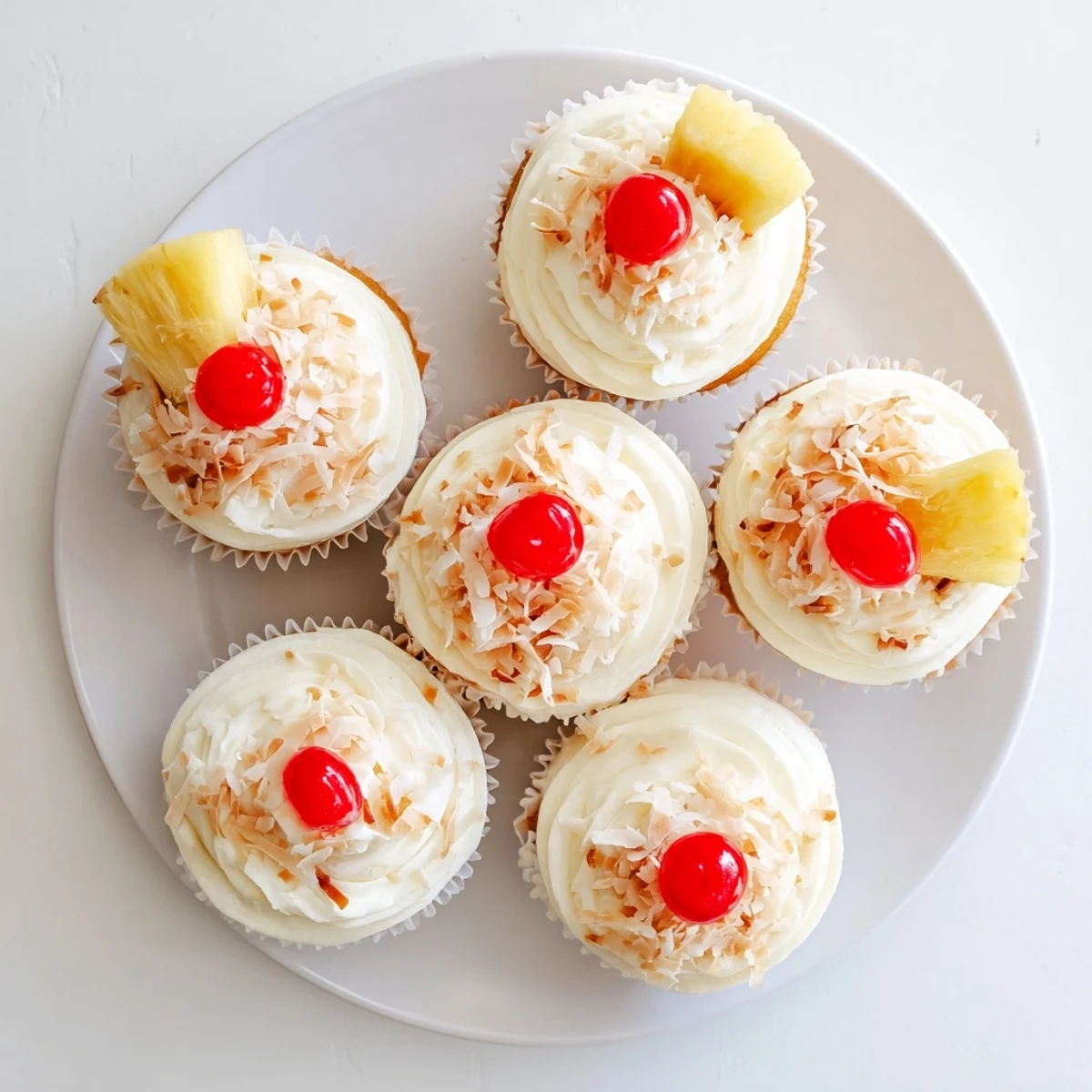 Tropical Piña Colada cupcakes with creamy white frosting and garnished pineapple wedges on serving platter
