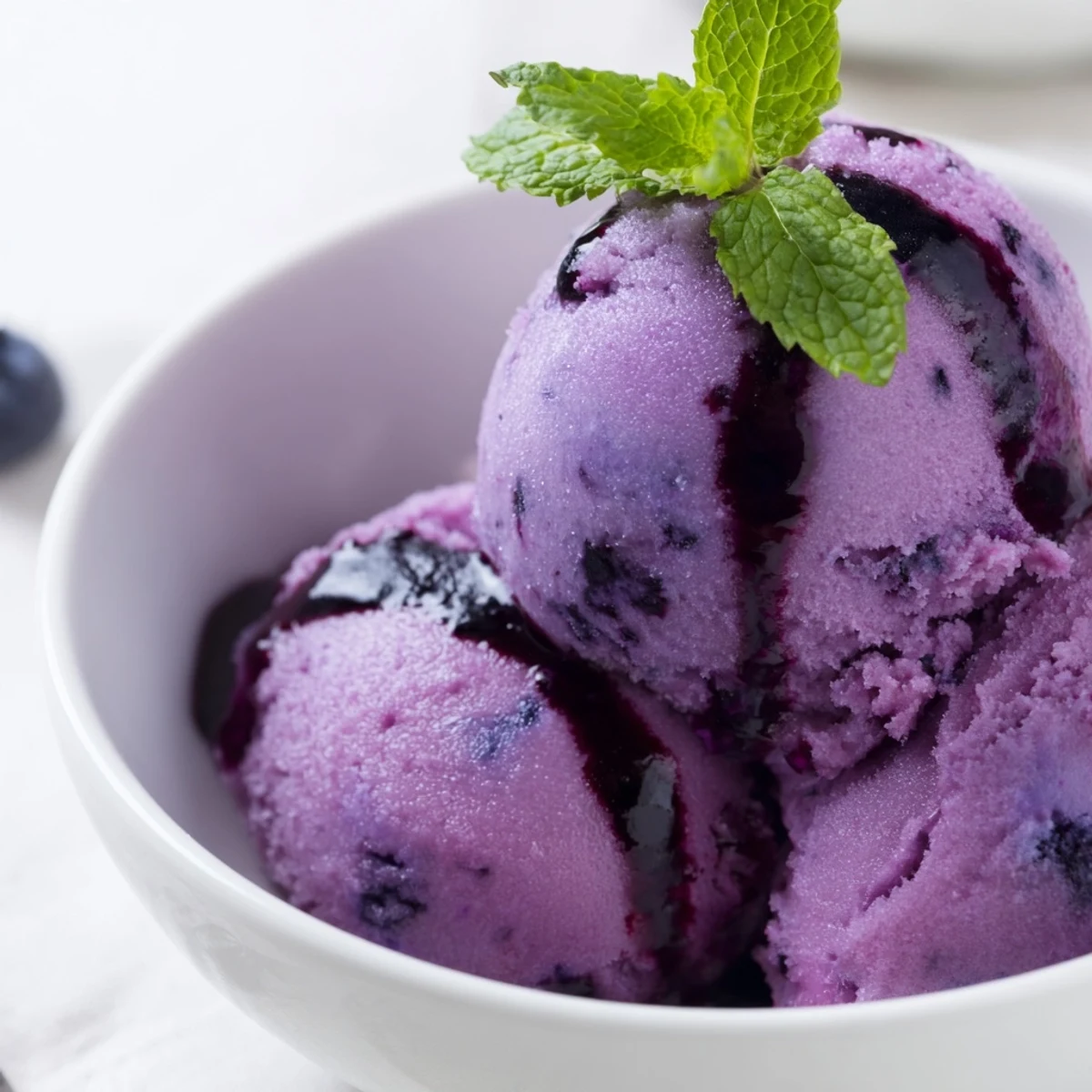 Vibrant purple no churn blueberry lemon sorbet scooped into a chilled glass bowl
