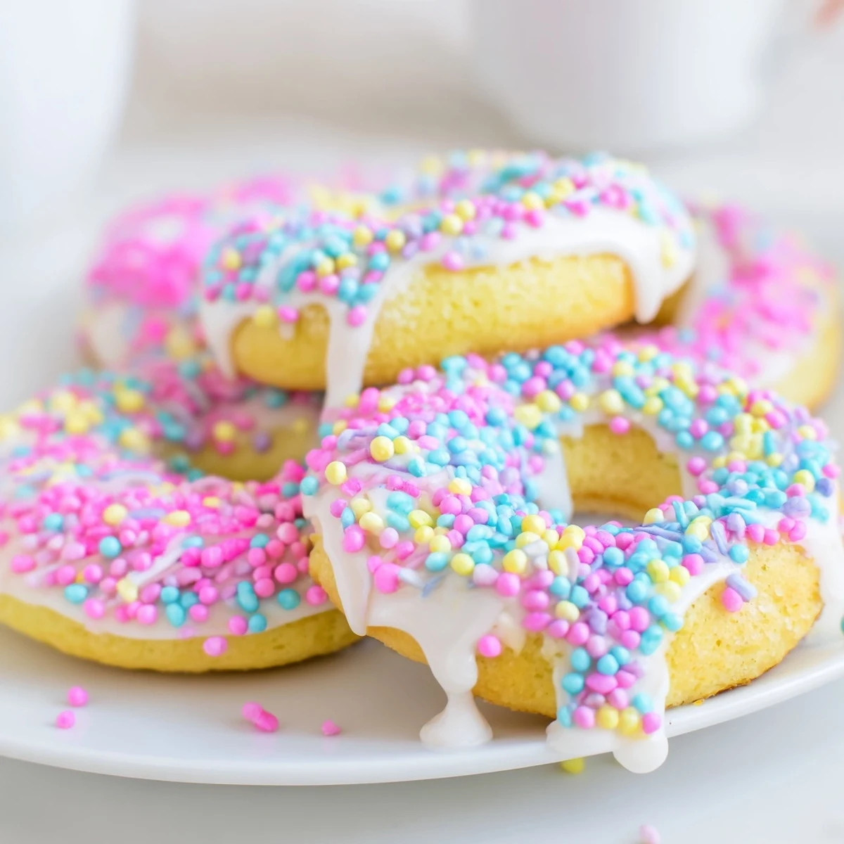 Baked ring-shaped Italian Easter cookies with lemon glaze and festive nonpareils resting on wire cooling rack