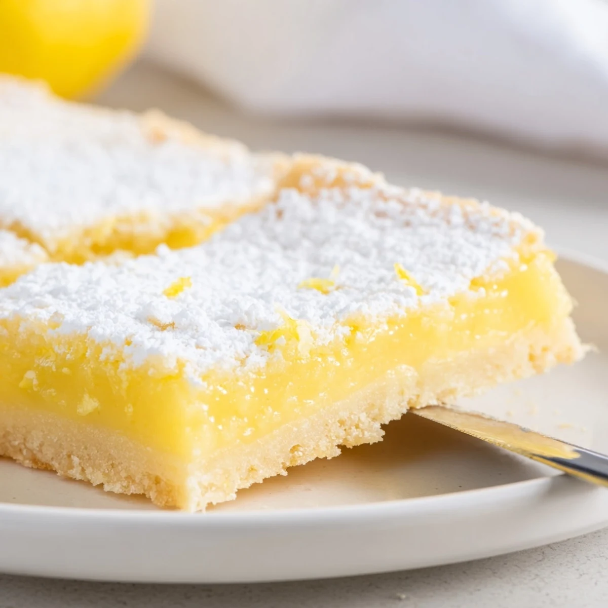 Tangy lemon bars cut into squares showing bright yellow filling and buttery crust