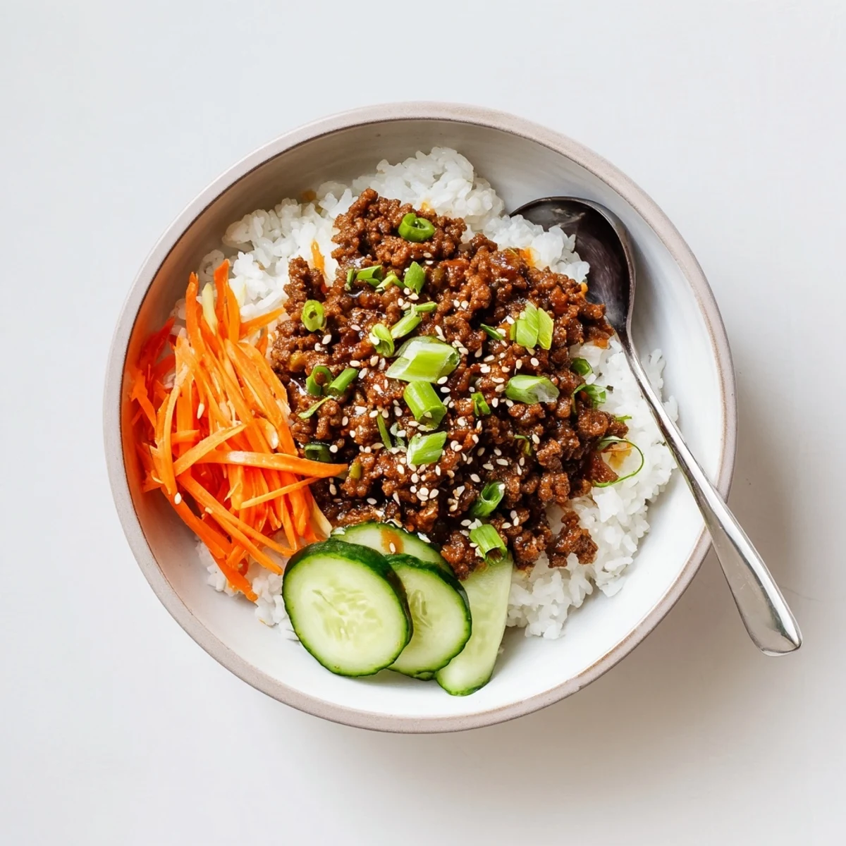 Savory Korean beef bowls topped with fresh vegetables and sesame seeds over fluffy white rice