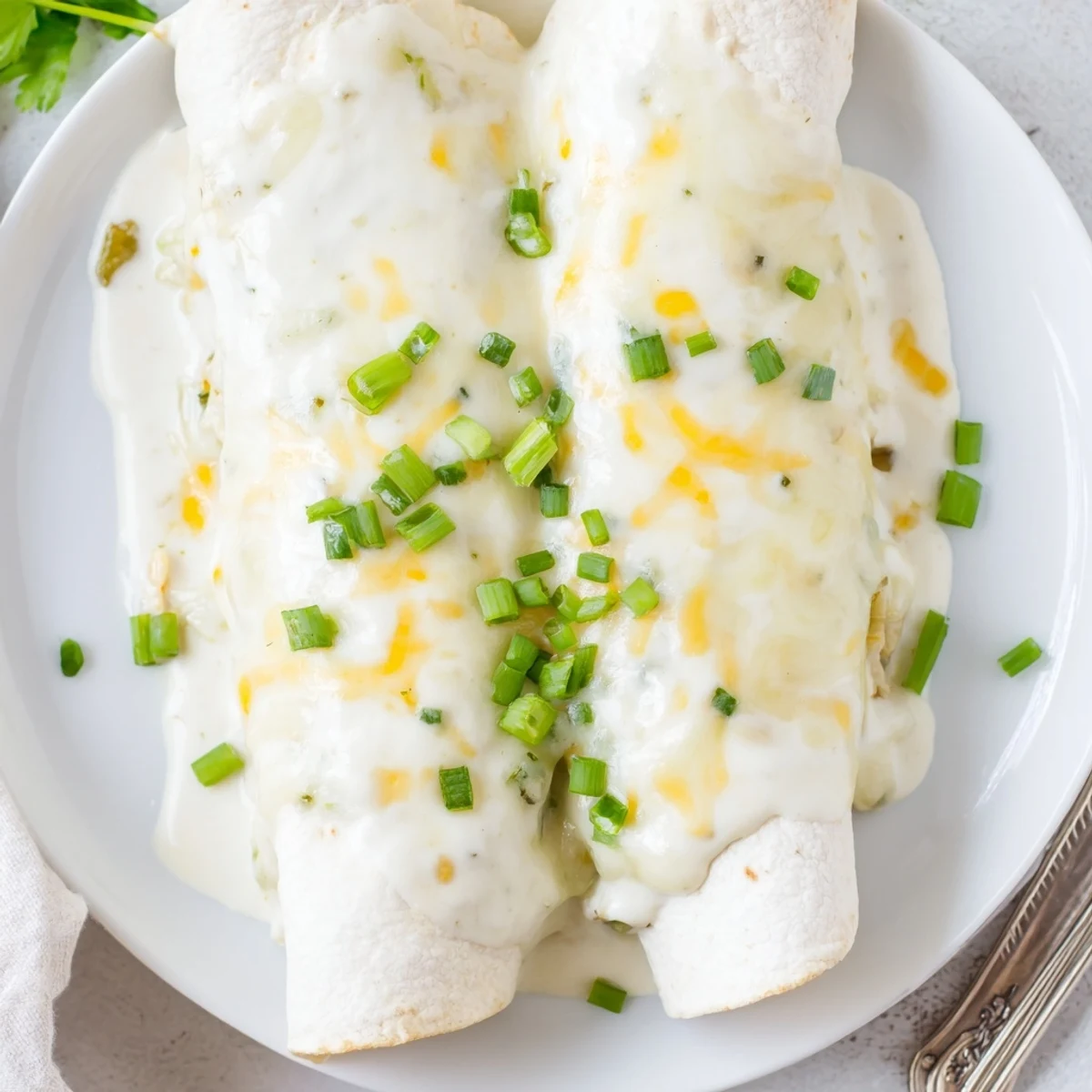 Bubbly, golden Creamy White Chicken Enchiladas in a 9x13 baking dish, garnished.  