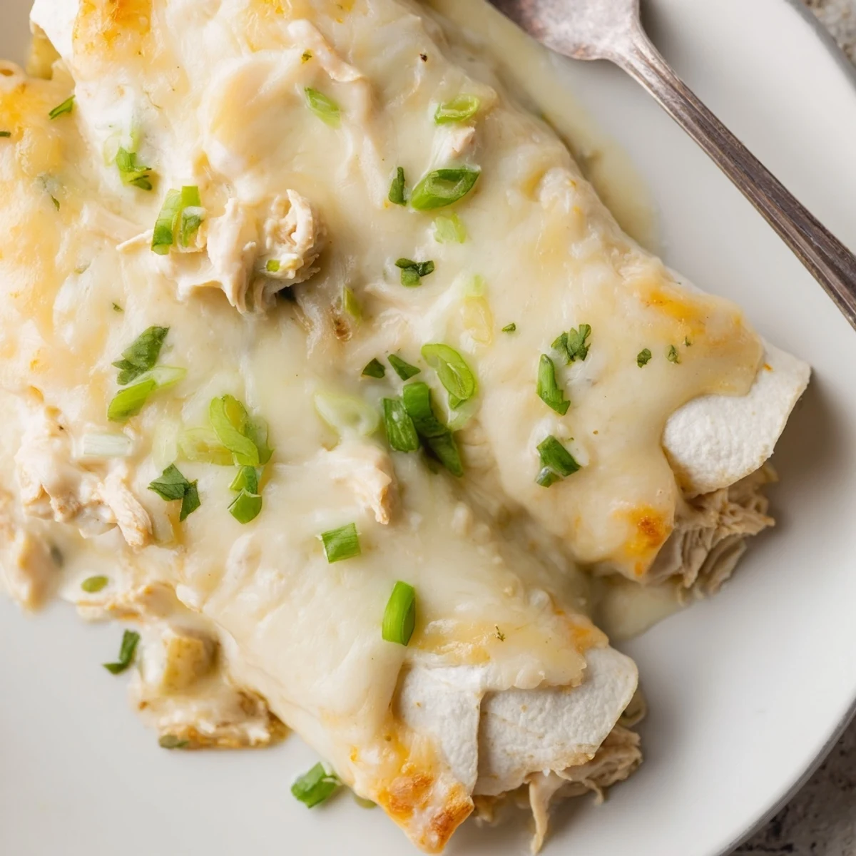 Family-style Creamy White Chicken Enchiladas topped with sour cream, served beside Spanish rice.