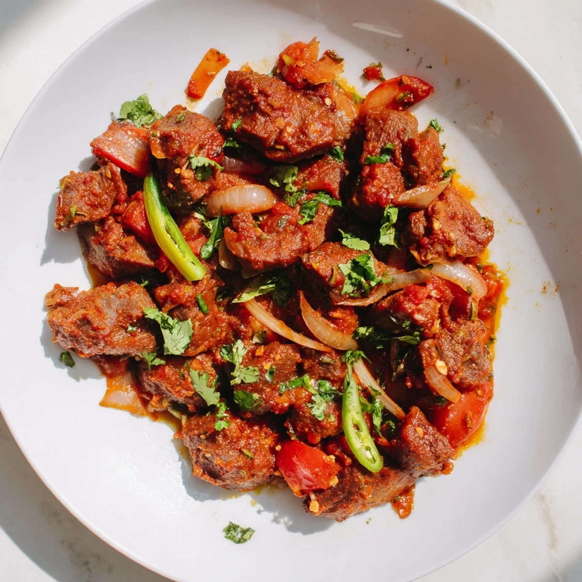Tender Kenyan goat wet fry simmered in rich tomato sauce with caramelized onions and fresh cilantro garnish