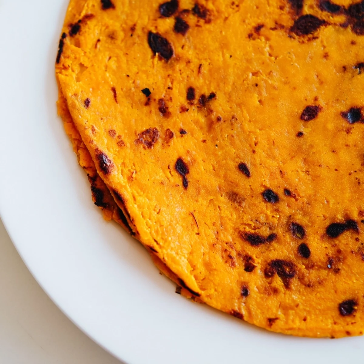 Golden-brown sweet potato cassava tortillas cooking in a cast iron skillet with visible brown spots