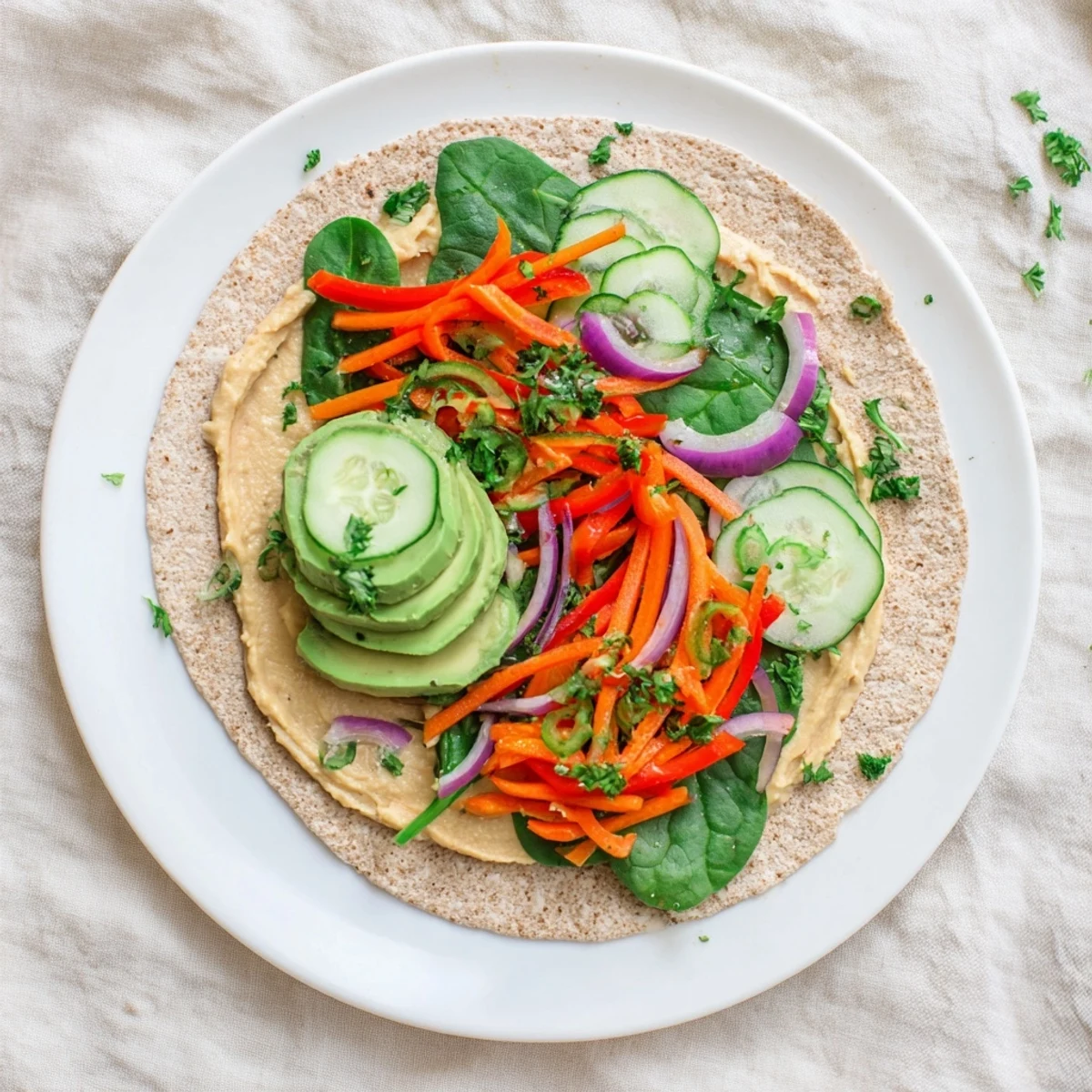 Plant-based wrap stuffed with classic hummus, baby spinach, red onion, and colorful veggies ready for a quick healthy meal