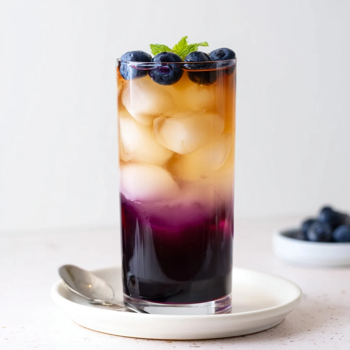 Blueberry Milk Tea Cooler with icy condensation, deep purple syrup swirl, mint garnish