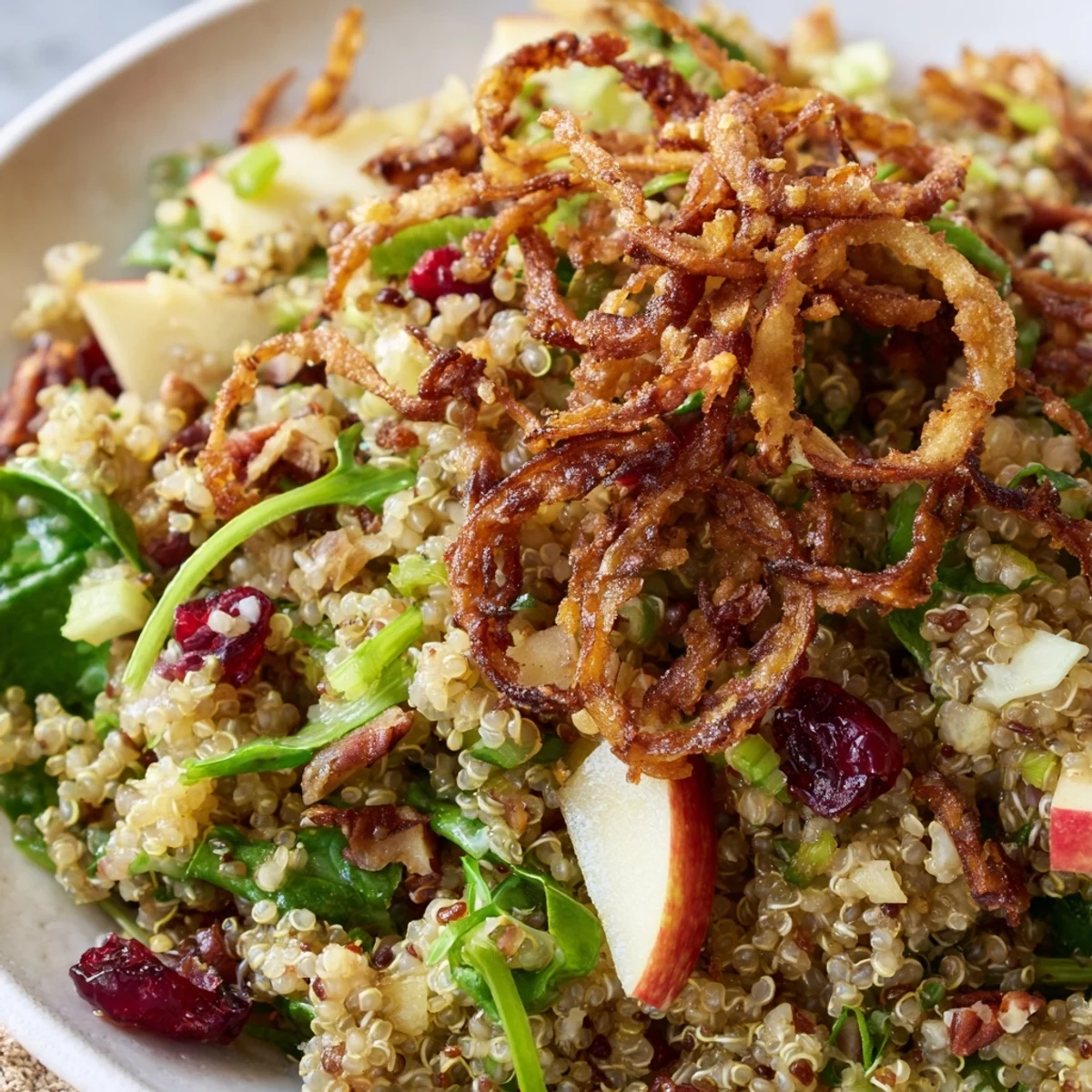Colorful honey mustard quinoa apple salad topped with golden crispy shallots and cranberries