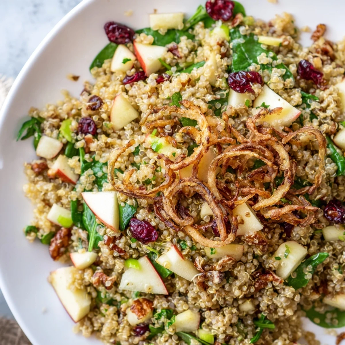 Fluffy quinoa tossed with crisp apples and tangy honey mustard dressing in a wooden bowl