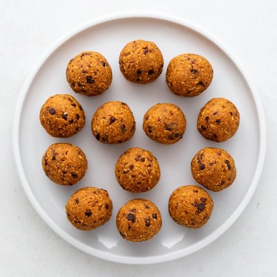Golden no bake pumpkin protein balls studded with chocolate chips in a chilled dish