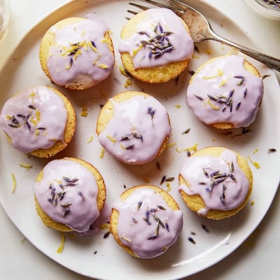 Tender mini lemon cakes with aromatic lavender glaze beside a steaming cup of tea