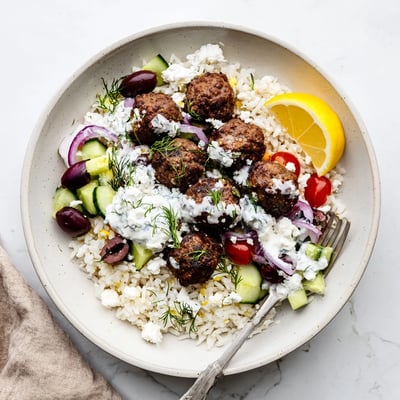 Juicy Greek meatball bowl served over rice with cherry tomatoes and olives